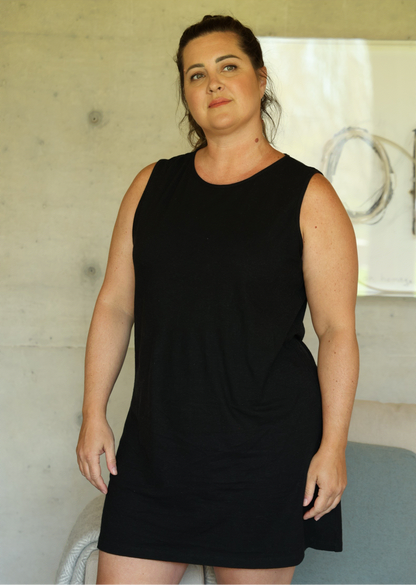 Woman wearing a black sleeveless dress indoors.