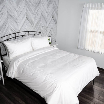 Bedroom with a bed of white organic cotton bedding against a wall with a chevron pattern