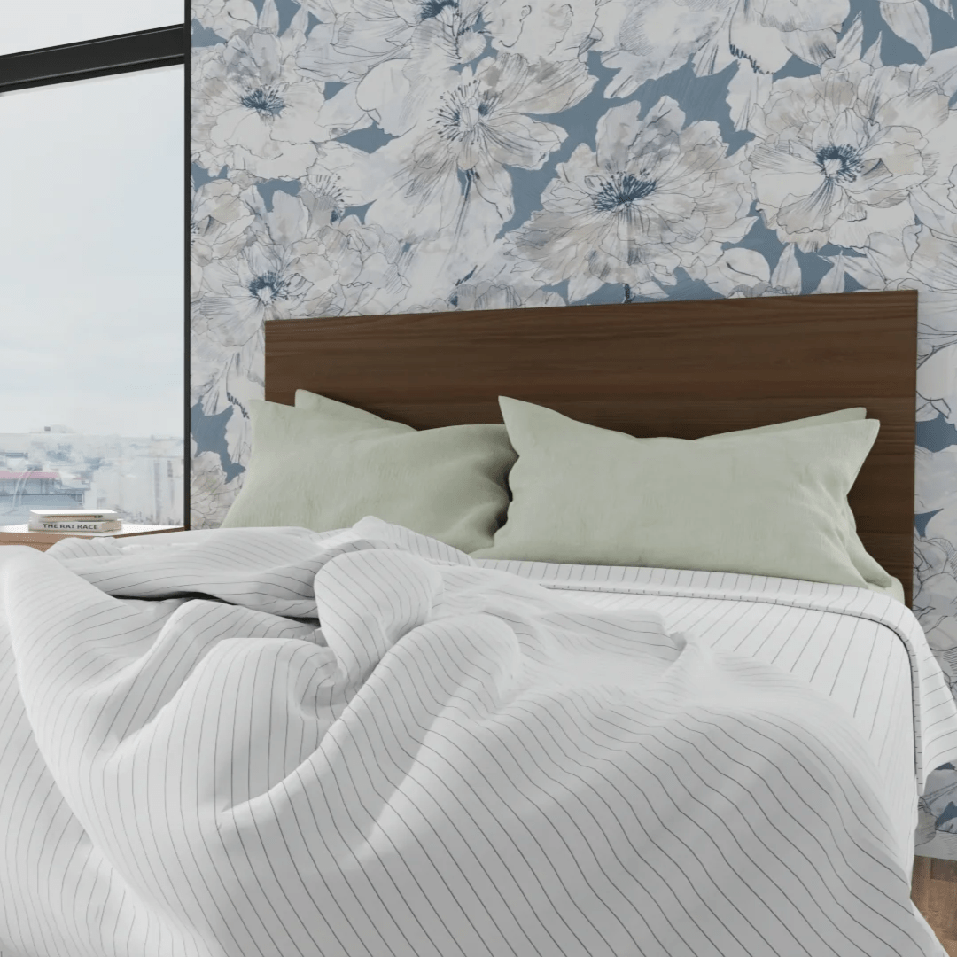Bed with wooden headboard and floral wallpaper in the background