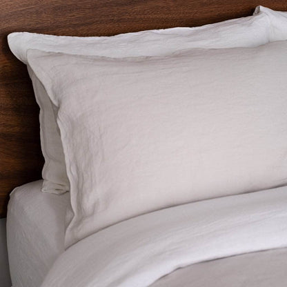 Close-up of beige pillows on a bed with a wooden headboard.