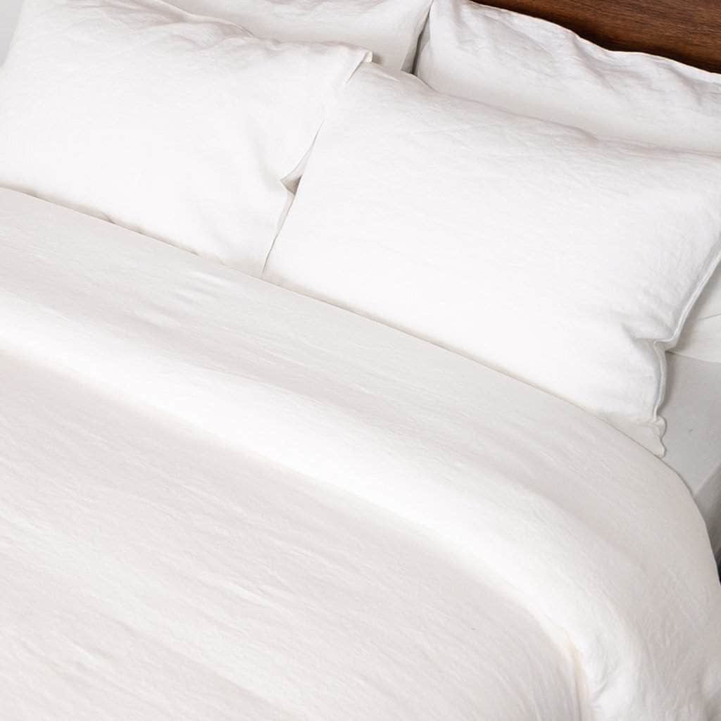 Close-up of white linen bedding with a soft texture on a bed.