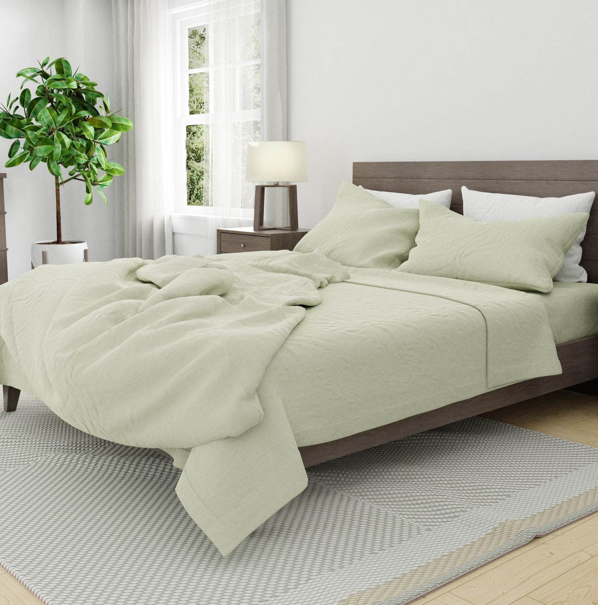 Bed with light green soft linen bedding in a bright bedroom