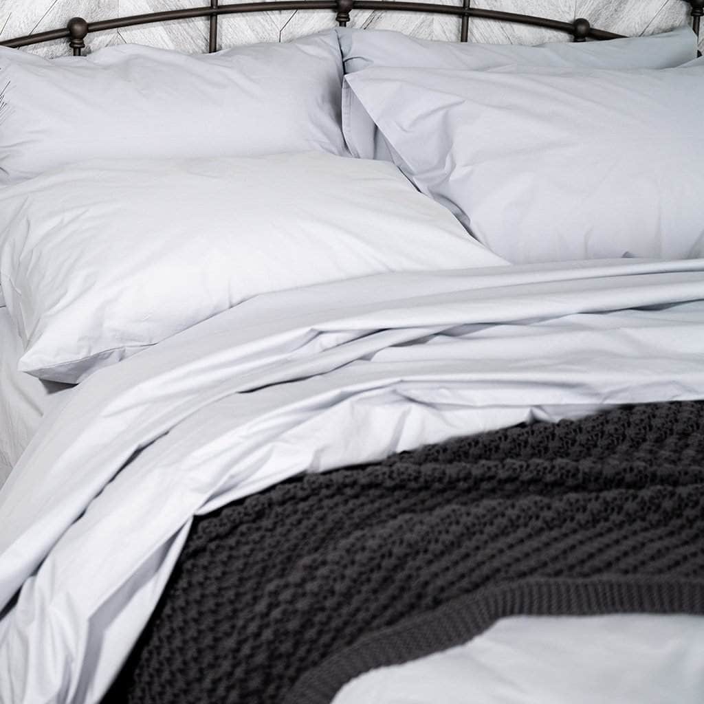 White organic cotton bedding on a bed with a dark headboard