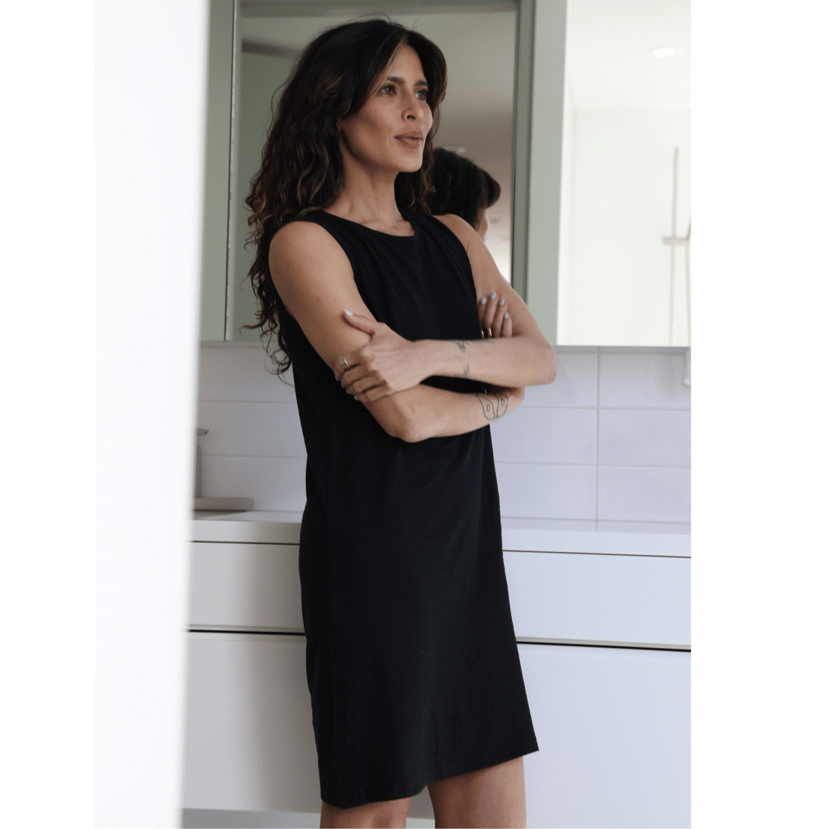 Woman in a black night gown  standing in a kitchen.