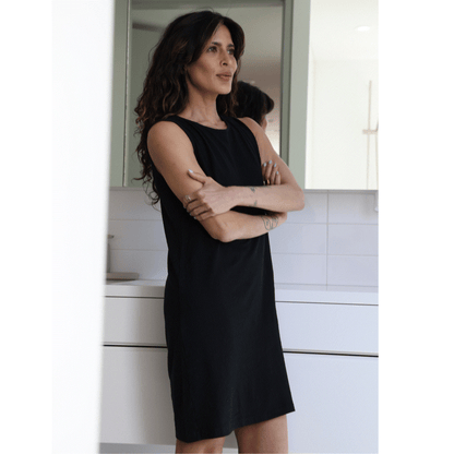 Woman in a black night gown  standing in a kitchen.